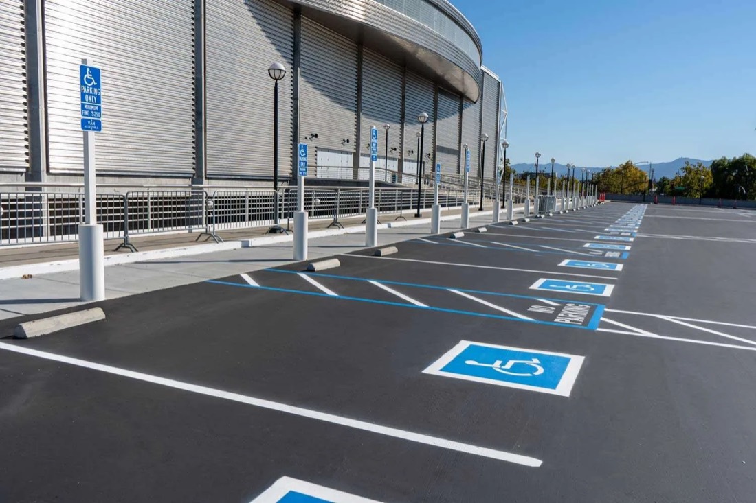 Freshly striped accessible parking stalls with blue wheelchair symbols, access-aisle hatching and ADA parking signs