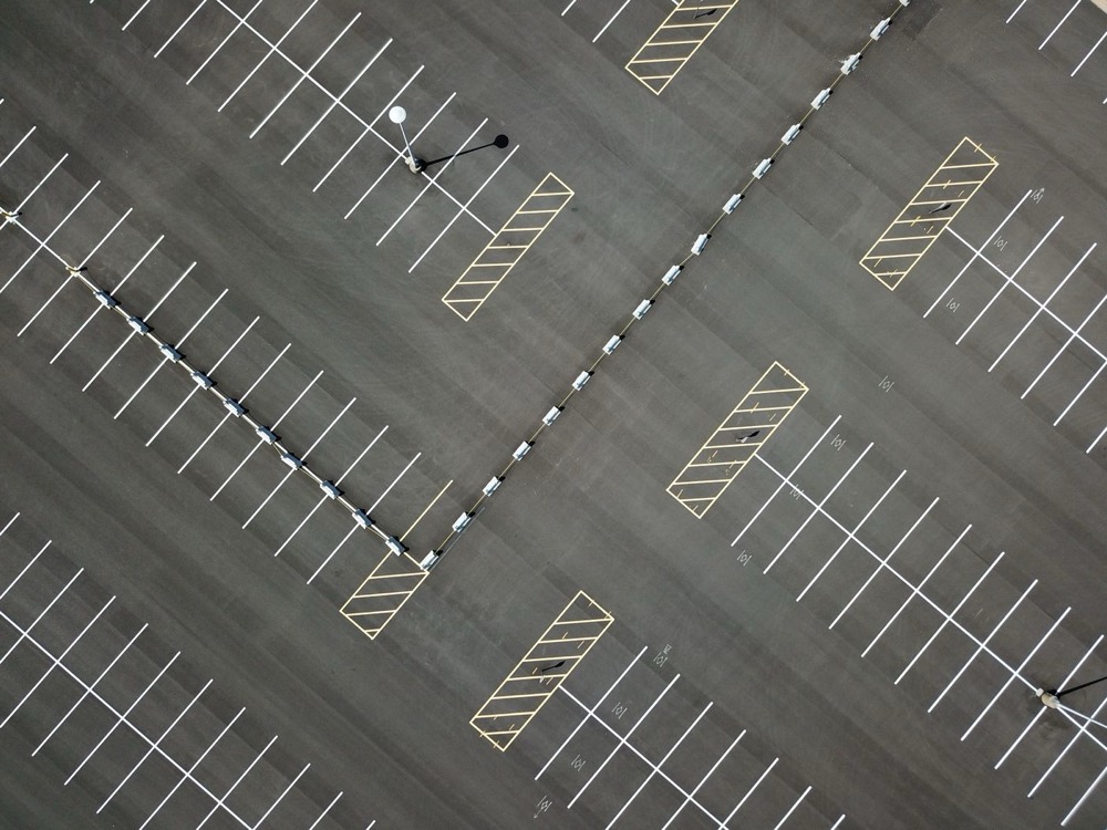 Freshly striped parking lot with crisp white stall lines and yellow hatched no-parking zones